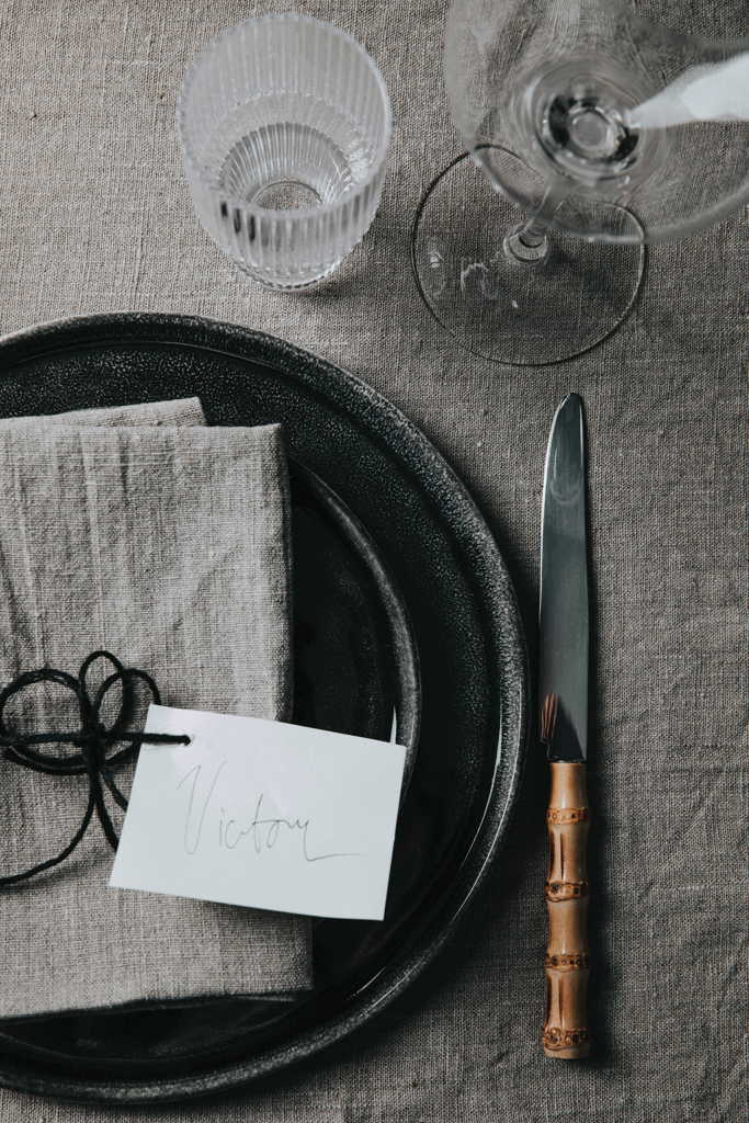 Teller, Besteck, Glas, Tischdeko, Notizkarte, Teller, Tischgedeck, Messer, Glas, Serviette, Teller, Besteck, Weißes Glas, Wein Glas, Tischdeko, Teller, Glas, Besteck, Tuch, Notizkarte